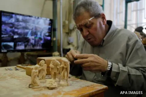 A Palestinian carpenter carves a wooden effigies of the the Holy Family at a workshop in the West Bank town of Bethlehem, on December 17, 2015. The traditional birthplace of Jesus Christ prepares to celebrate Christmas l...