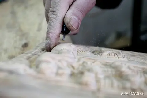 A Palestinian carpenter carves a wooden effigies of the the Holy Family at a workshop in the West Bank town of Bethlehem, on December 17, 2015. The traditional birthplace of Jesus Christ prepares to celebrate Christmas l...