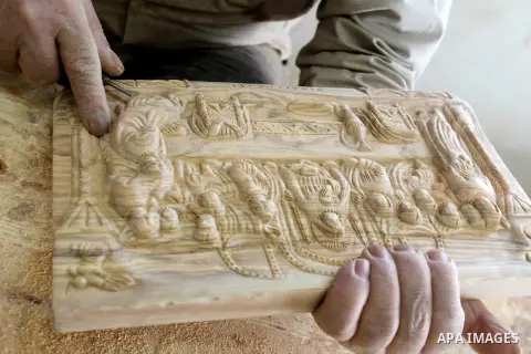 A Palestinian carpenter carves a wooden effigies of the the Holy Family at a workshop in the West Bank town of Bethlehem, on December 17, 2015. The traditional birthplace of Jesus Christ prepares to celebrate Christmas l...