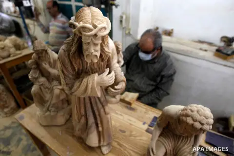 A Palestinian carpenter carves a wooden effigies of the the Holy Family at a workshop in the West Bank town of Bethlehem, on December 17, 2015. The traditional birthplace of Jesus Christ prepares to celebrate Christmas l...