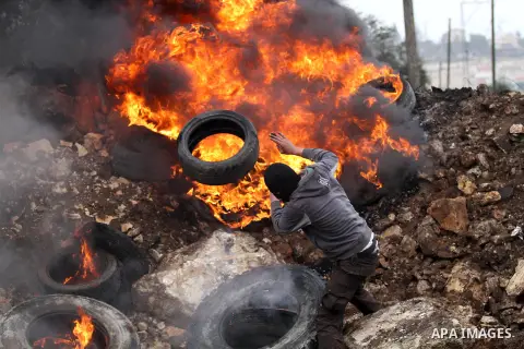 A Palestinian protester burns tires during clashes with Israeli security forces following a demonstration against the expropriation of Palestinian land by Israel in the village of Kfar Qaddum, near Nablus in the occupied...