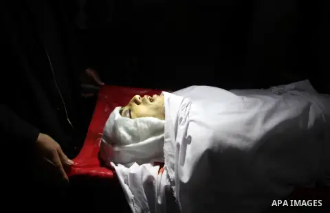 Mourners gather around the body of Palestinian Mahmoud Al-Aga, 20, whom medics said was killed by Israeli troops during clashes with Palestinian protesters on Friday, during his funeral in Khan Younis in the southern of...