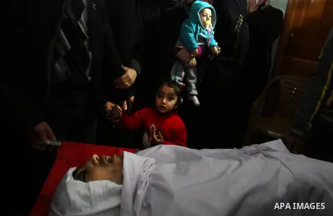 Mourners gather around the body of Palestinian Mahmoud Al-Aga, 20, whom medics said was killed by Israeli troops during clashes with Palestinian protesters on Friday, during his funeral in Khan Younis in the southern of...