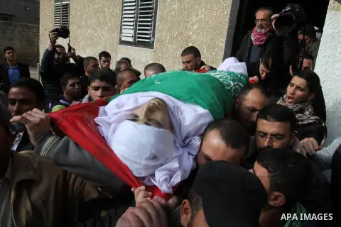 Mourners carry the body of Palestinian Mahmoud Al-Aga, 20, whom medics said was killed by Israeli troops during clashes with Palestinian protesters on Friday, during his funeral in Khan Younis in the southern of Gaza Str...