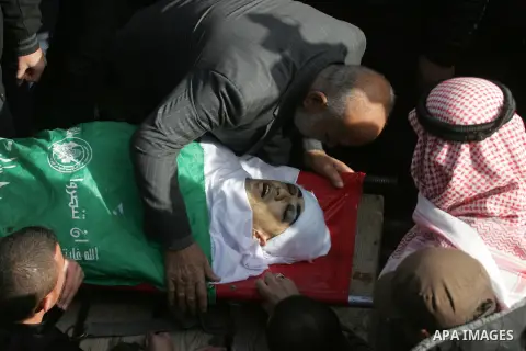 Mourners gather around the body of Palestinian Mahmoud Al-Aga, 20, whom medics said was killed by Israeli troops during clashes with Palestinian protesters on Friday, during his funeral in Khan Younis in the southern of...
