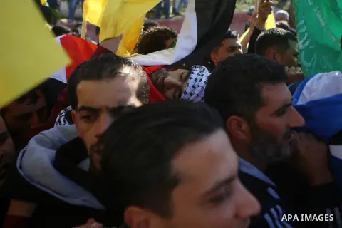 Mourners carry the body of Palestinian Nashat Asfour, who was killed from clashes with Israeli troops Friday, is covered with flowers during his funeral in the West Bank village of Sinjil, near Ramallah, Saturday, Dec. 1...