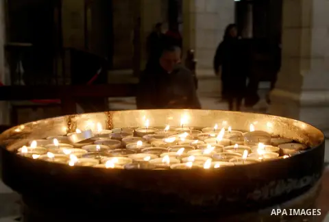 A Christian worshipper lights a candle at the Church of the Nativity, believed to be the birthplace of Jesus Christ, in the West Bank city of Bethlehem, on December 20, 2015. Photo by Wisam Hashlamoun