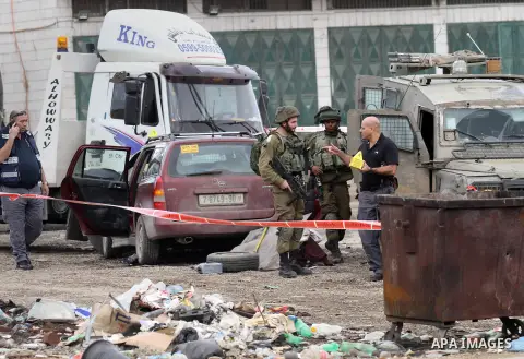 Israeli security forces gather at the site of a car ramming attack in the village of Hawara near the West Bank city of Nablus, on December 31, 2015. A Palestinian drove his car into Israeli forces before being shot dead,...