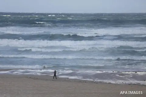 A Palestinian walks past the beach of Gaza city as waves crash fishermen's harbor on the first day of the new year on Jan. 01, 2016. Photo by Mohammed Asad