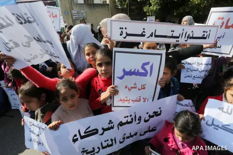 Palestinians hold banners during a protest demanding the Egyptian authorities for the opening of the Rafah crossing in front of the Egyptian embassy, in Gaza city, on January 14, 2016. Photo by Mohammed Asad