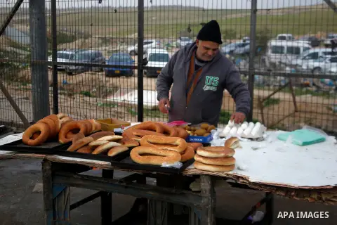 A Palestinian working in Israel buys food from a vendor as he waits to cross through the Israeli-controlled Mitar checkpoint south of the West Bank city of Hebron January 19, 2016. Photo by Wisam Hashlamoun