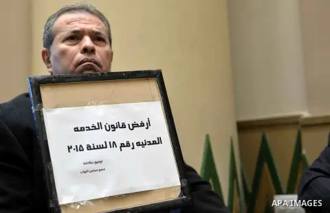 Tawfiq Okasha, a pro-government TV anchorman who was elected to parliament, sits in an anteroom and holds banners against Civil Service Law during a parliamentary session, in Cairo, Egypt in Jan. 19, 2016. Photo by Amr S...