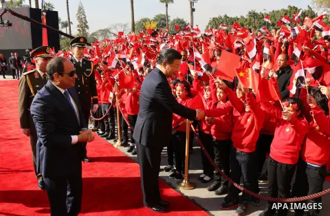 Children carrying Chinese flags cheer as Egyptian President Abdel Fattah al-Sisi (L) walks with Chinese President Xi Jinping (R) at the presidential palace during their meeting in Cairo, Egypt, January 21, 2016, in this...