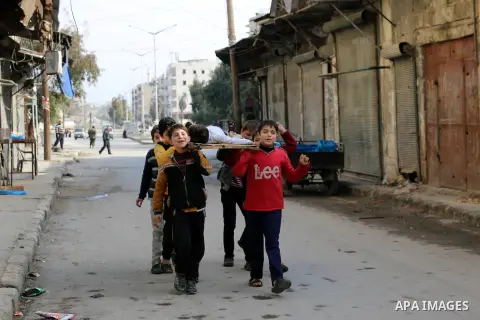 Syrian children carry the body of their friend as they play in a symbolic funeral in the northern Syrian city of Aleppo, on Jan. 22, 2016. Photo by Ameer al-Halbi