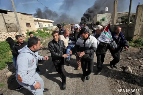 Palestinians carry a wounded protester during clashes with Israeli security forces following a protest against the expropriation of Palestinian land by Israel in the West Bank village of Kafr Qaddum, near the northern ci...