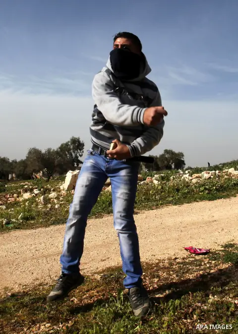 A Palestinian protester hurls stones toward Israeli security forces during clashes following a protest against the expropriation of Palestinian land by Israel in the West Bank village of Kafr Qaddum, near the northern ci...