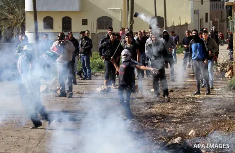 A Palestinian protester uses a slingshot to throw back a canisters fired by Israeli secrity forces during clashes following a protest against the expropriation of Palestinian land by Israel in the West Bank village of Ka...