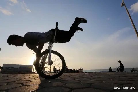 A Palestinian youth performs stunts with bicycles on the beach of the Mediterranean Sea in Gaza City on Jan. 22, 2016. Photo by Mohammed Asad
