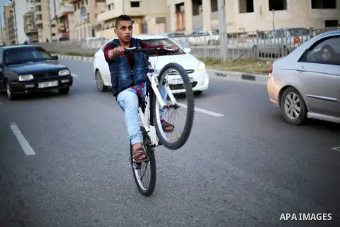 A Palestinian youth performs stunts with bicycles on the beach of the Mediterranean Sea in Gaza City on Jan. 22, 2016. Photo by Mohammed Asad