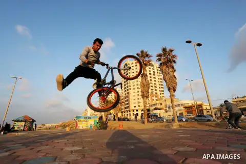 A Palestinian youth performs stunts with bicycles on the beach of the Mediterranean Sea in Gaza City on Jan. 22, 2016. Photo by Mohammed Asad