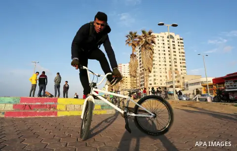 A Palestinian youth performs stunts with bicycles on the beach of the Mediterranean Sea in Gaza City on Jan. 22, 2016. Photo by Mohammed Asad