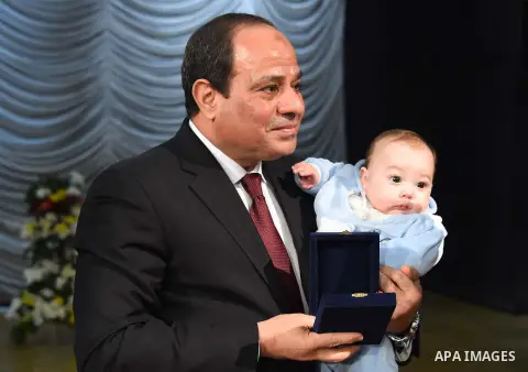 Egyptian President Abdel-Fattah el-Sissi holds a child as he presents a medal to the widow of a policeman killed in militant attacks, at a ceremony marking Police Day, which falls on Jan. 25, the anniversary of the 2011...