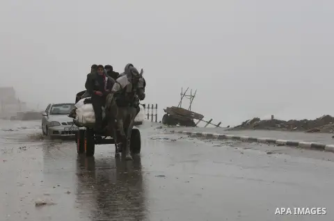 Palestinian men ride a donkey cart in a street flooded by rain water, in Gaza City, January 24, 2016. Photo by Mohammed Asad