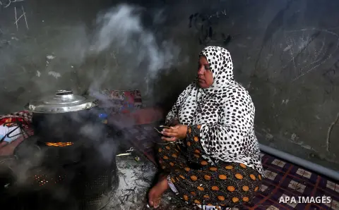 A Palestinian woman cooks food on a rainy day, in Khan Younis in the southern Gaza Strip, January 24, 2016. Photo by Yasser Qudih
