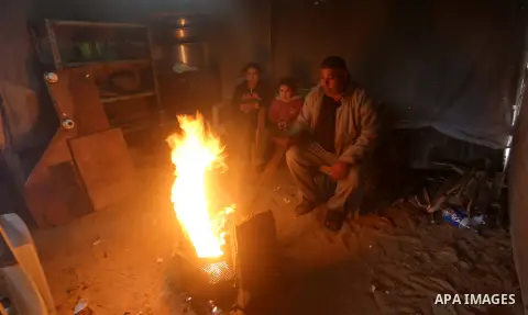 Members of a Palestinian famil warm themselves next to a fire during a rainy day, in Khan Younis in the southern Gaza Strip, January 24, 2016. Photo by Yasser Qudih