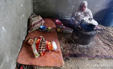 A Palestinian woman cooks food on a rainy day, in Khan Younis in the southern Gaza Strip, January 24, 2016. Photo by Yasser Qudih