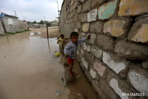 Palestinian boys cross a road flooded with rainwater following heavy rains, in Khan Younis in the southern Gaza Strip January 24, 2016. Photo by Yasser Qudih