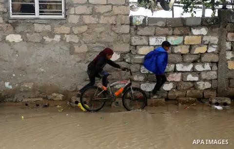 Palestinian boys cross a road flooded with rainwater following heavy rains, in Khan Younis in the southern Gaza Strip January 24, 2016. Photo by Yasser Qudih