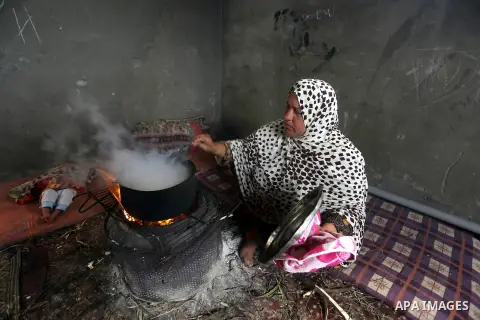 A Palestinian woman cooks food on a rainy day, in Khan Younis in the southern Gaza Strip, January 24, 2016. Photo by Yasser Qudih
