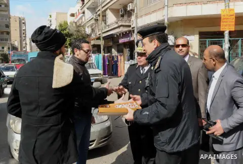 Egyptian policemen give out chocolates to citizens on Cairo's landmark Tahrir Square on January 25, 2016, as the country marks the fifth anniversary of the 2011 uprising. Egyptians marked the fifth anniversary of the upr...