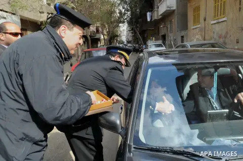 Egyptian policemen give out chocolates to citizens on Cairo's landmark Tahrir Square on January 25, 2016, as the country marks the fifth anniversary of the 2011 uprising. Egyptians marked the fifth anniversary of the upr...