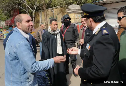 Egyptian policemen give out chocolates to citizens on Cairo's landmark Tahrir Square on January 25, 2016, as the country marks the fifth anniversary of the 2011 uprising. Egyptians marked the fifth anniversary of the upr...