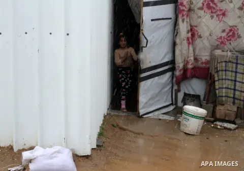 A Palestinian girl peaks from inside her temporary housing during a winter storm in the southern Gaza Strip town of Khan Younis on January 25, 2016. Photo by Abed Rahim Khatib