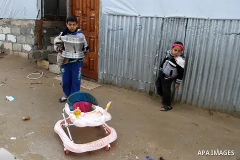 Palestinian children walk past temporary housing during a winter storm in the southern Gaza Strip town of Khan Younis on January 25, 2016. Photo by Abed Rahim Khatib