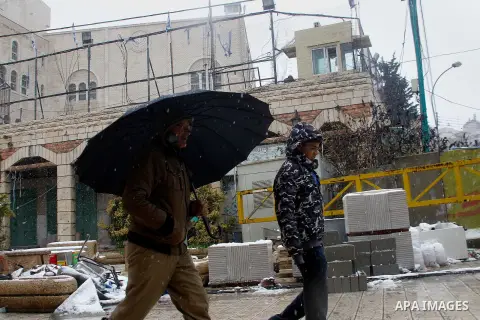 Palestinians walk during a snowstorm in the West Bank city of Hebron, on January 26, 2016. Photo by Wisam Hashlamoun
