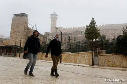 Palestinians walk during a snowstorm in the West Bank city of Hebron, on January 26, 2016. Photo by Wisam Hashlamoun