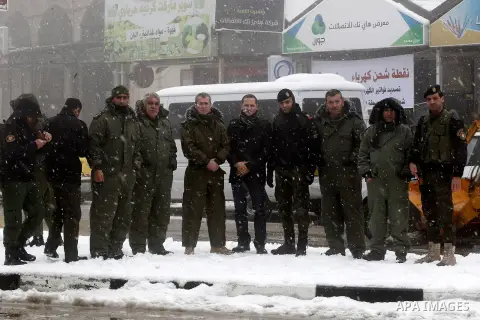 Palestinian National Security stand as they help citizens during a snowstorm in the West Bank city of Hebron, on January 26, 2016. Photo by Wisam Hashlamoun