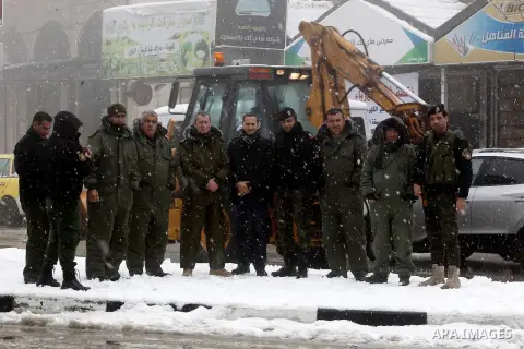 Palestinian National Security stand as they help citizens during a snowstorm in the West Bank city of Hebron, on January 26, 2016. Photo by Wisam Hashlamoun