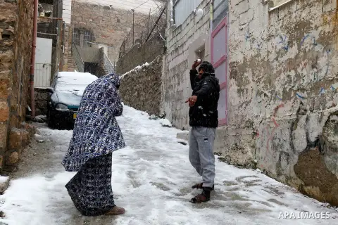 A Palestinian man plays with snow during a snowstorm in the West Bank city of Hebron, on January 26, 2016. Photo by Wisam Hashlamoun