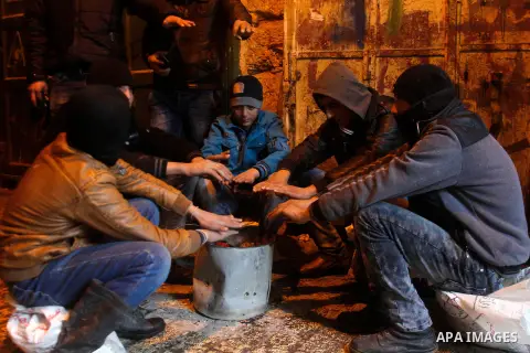 Palestinians warm themselves around a fire during a heavy winter storm in the West Bank city of Hebron, on January 26, 2016. Photo by Wisam Hashlamoun