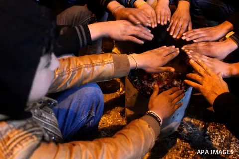 Palestinians warm themselves around a fire during a heavy winter storm in the West Bank city of Hebron, on January 26, 2016. Photo by Wisam Hashlamoun