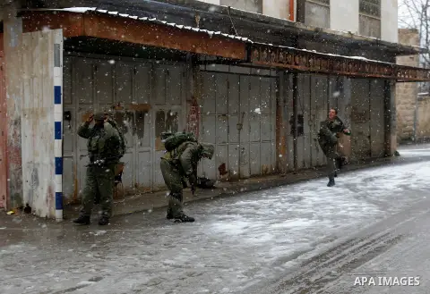 Israeli security forces play with snow during a snowstorm in the West Bank city of Hebron, on January 26, 2016. Photo by Wisam Hashlamoun