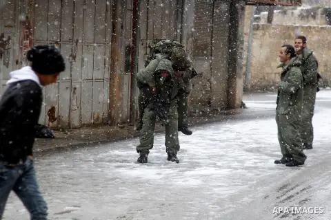 Israeli security forces play with snow during a snowstorm in the West Bank city of Hebron, on January 26, 2016. Photo by Wisam Hashlamoun