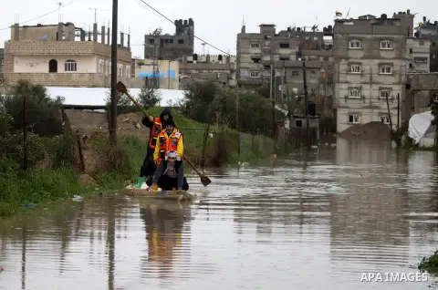 Palestinian Civil Defence workers use a stand-up kayak to evacuate people from a flooded area following heavy rainfall in the southern Gaza Strip town of Rafah on January 26, 2016. Photo by Abed Rahim Khatib