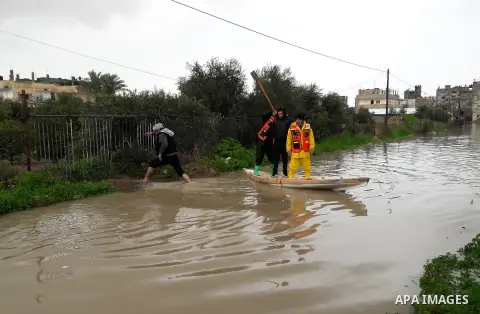 Palestinian Civil Defence workers use a stand-up kayak to evacuate people from a flooded area following heavy rainfall in the southern Gaza Strip town of Rafah on January 26, 2016. Photo by Abed Rahim Khatib