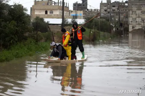 Palestinian Civil Defence workers use a stand-up kayak to evacuate people from a flooded area following heavy rainfall in the southern Gaza Strip town of Rafah on January 26, 2016. Photo by Abed Rahim Khatib